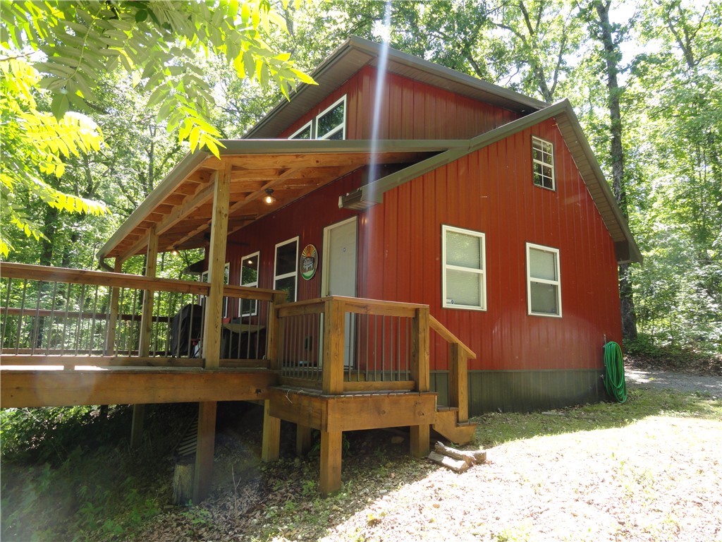 Tucked away near the end of a dead-end road, this move-in-ready, beautifully crafted cabin on 7.65 surveyed acres offers privacy, comfort, and really nice views of the distant hills. The property can be used for a vacation get-a-way, Airbnb, forever home or an escape property in the middle of the Boston Mountains. Featuring 2 bedrooms and 1.5 baths, the home showcases vinyl plank flooring, wooden stairs, rich wood trim and accents, and tasteful décor throughout. Large windows bring in natural light and capture the scenic surroundings from nearly every room. Enjoy the outdoors from the 14’x24’ deck, half covered for year-round relaxation. Exterior features low-maintenance metal siding and a metal roof. A 24’x32’ spray foam insulated metal shop building includes a concrete floor, electricity, lighting, and water line stubbed in—ready for your projects or storage needs. Located only 3.5 miles from the Buffalo National River and Gilbert, AR, this property is the perfect blend of seclusion and convenience.