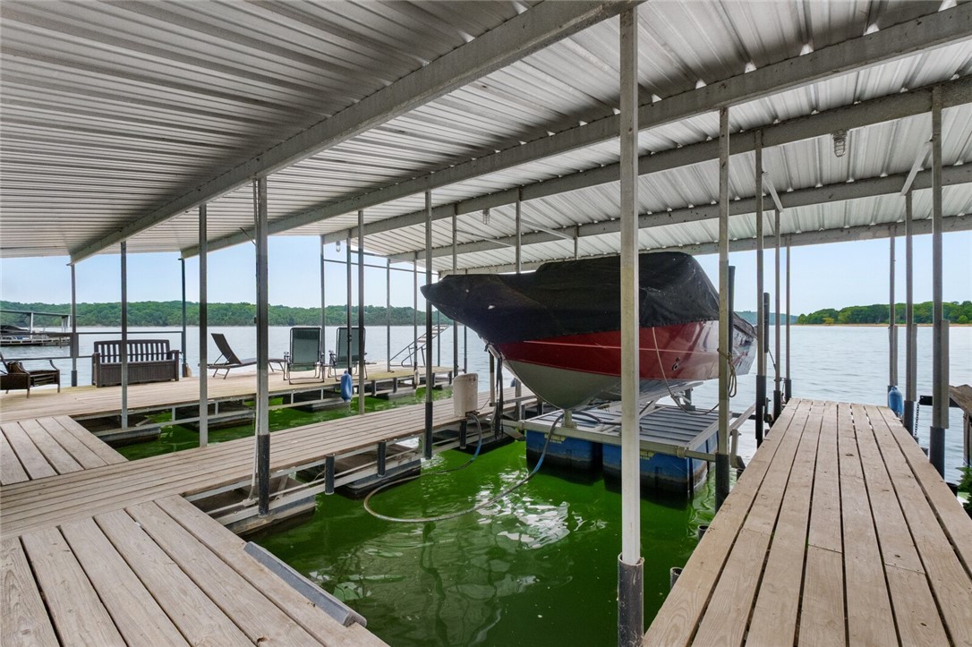 Lakefront showstopper featuring soaring glass panels that bring the outdoors in. A rare find, this property is just steps away from the co-owned 4-slip boat dock w/swim deck. Two 10' x 26' slips & lifts convey.  This 4,374 SF retreat balances luxury with comfort, offering multiple entertainment areas that flow seamlessly from indoors to outdoors. The main-level primary suite is a sanctuary including a sitting area, spa-inspired en suite bath and separate laundry room. A second Primary, Family Room, and Laundry Room are located on the lower level, along with an office and fitness room. Significant updates include a remodel of all five bathrooms, installing hardwood floors, new roof, 3 HVAC units, whole-house generator, new septic system, and fresh interior/exterior paint. This is a rare opportunity to claim the lakefront retreat you've long desired.