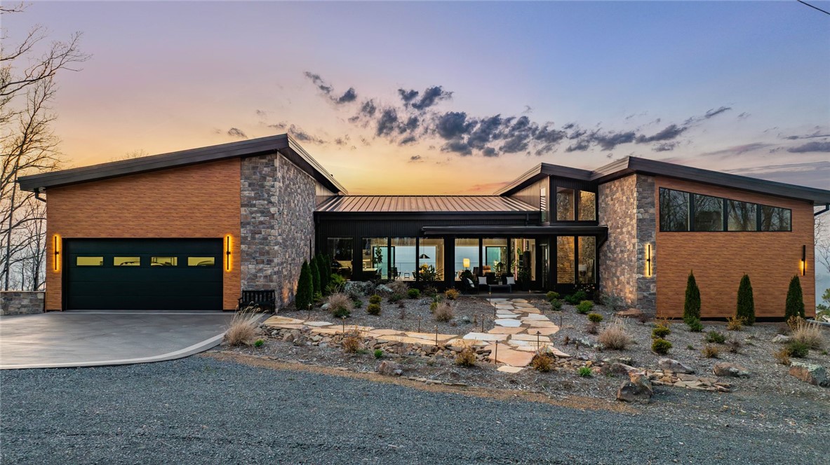 Designed by Polk Stanley Wilcox Architects and engineered into one of the Ozarks' most commanding ridgelines, this generational contemporary estate on twelve private, gated acres above the vast horizon of Greers Ferry Lake redefines what luxury in Arkansas can be. Built to endure for generations — thirty tons of steel, 350 yards of concrete, hand-laid natural stone, and floor-to-ceiling glass framing unobstructed panoramic views from nearly every room in the home. More than 6,500 square feet of exceptional turnkey living unfolds beneath soaring knotty pine ceilings and exposed steel beams. The chef's kitchen is appointed without compromise, centered on a stunning book-matched marble island. The primary suite offers a thermal air soaking tub, private fireplace, and uninterrupted lake views. A commercial fitness suite, sauna, whole-home automation, whole-home audio, storm shelter, and whole-house generator complete an offering that stands entirely without parallel in this market.