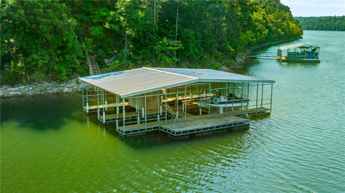 RARE Beaver Lake Retreat with It ALL! 2018 Custom-built on 11.87 Private acres with Yr. Round LAKE VIEWS. This LAKEFRONT property offers 2 Boat Slips on a Private Co-Owned Dock, a Guest House, and Shop, NO restrictions, endless opportunities. Designed for entertaining and everyday living, the open floorplan features a gourmet kitchen with expansive island and seamless flow to a screened-in patio overlooking the lake. The main level has STUNNING lake views from all of the living areas, includes a spa-like primary suite, two additional bedrooms, media room, and office space. The walk-out lower level boasts a huge bonus room, additional bedroom, and full bath. An 820-sq-ft Guest House with full kitchen, living room, 2BR and full bath is perfect for guests, in-laws, or rental income. The dock, 2 slips, oversized locker, and swim platform with easy access by side-by-side or SUV, The ultimate setting for lake days, sunset cruises, and unforgettable memories with family and friends. Call Agent full list of upgrades.