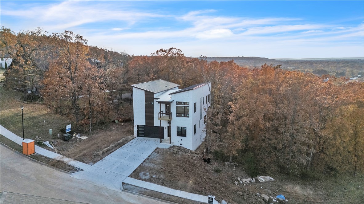 Discover 2351 Windswept Lane, a brand-new, luxurious Fayetteville residence. Perched on a hilltop, this home offers breathtaking panoramic city views. The 3367 sq. ft. home features 4 spacious bedrooms, an office/bonus space, a solarium, and 4.5 bathrooms with floating vanities. High ceilings (12' on the 1st floor, 10' on the 2nd) enhance the expansive feel. The exterior boasts premium Mac Metals and classic white brick, and an expansive rear covered deck. Inside, find engineered hardwood and unique tile selections, & quartz counters. Walls and ceilings feature dynamic 3D modern design features, and the north wall is adorned with custom windows on both floors. The chef's kitchen is equipped with SMART LG appliances and a gourmet pot filler. The primary bath has a freestanding tub, and the living area includes a modern fireplace. Located in a highly desirable school district, the home's prime location is close to Gulley Park, HWY 49, the University of Arkansas, and NWA Mall.