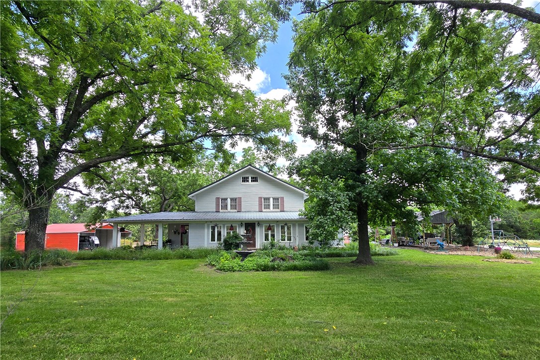 Located on an impressive 95 acres just beyond the city limits of Berryville, you will find a storybook farmhouse setting under a canopy of large hardwood trees. Originally built in 1900, this home holds all the memories and historic charm of yesteryear while offering all the comforts of today.  Inside you will find 4 large bedrooms, 2.5 updated bathrooms, a stunning kitchen with granite countertops and an industrial propane range and hood, a dining room with sunlight pouring in, a living room with welcoming ambiance, enhanced by a classic brick fireplace, wood floors, a sunroom with a wet bar, office space at the bottom of the historic staircase, and so much more!  Outside, you will want to relax under the covered gazebo, on the patio with a firepit, or shooting hoops on your home court.  Acreage is fully fenced (pipe and wire) and offers 950’ of highway frontage! Carports will convey. Tankless propane water heater. Private well and septic. Storm Shelter. This dream home and farm won't last long, come see it today!