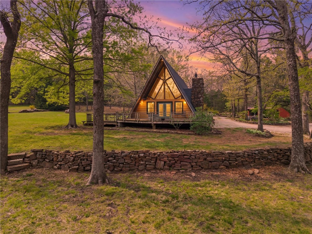 Whether you are looking for a permanent home or a weekend retreat, this property has a lot to offer. Surrounded on three sides by rolling hills and natural forest, the peaceful valley setting is beautiful in all seasons, but stunning in the fall. Minutes from Historic Canehill, the remodeled A-frame home sits just down a well-maintained gravel road with easy access from Fayetteville, Ft. Smith, or Siloam Springs. Nice mixture of woods and open fields along with a pond and wet weather creek. ATV trails run throughout the property. The end-of-the-road location offers privacy, seclusion, and peace. The charming cabin has been completely remodeled but retains the 1970s charm with its vaulted ceilings, wall of windows, stone fireplace, and original pine floors. Don’t miss the recent (2025) barn conversion with its additional bath, full kitchen, and extra storage. There is City water and a well that is plumbed to supply the A-frame, guesthouse, and gardens. Additional acreage available see MLS 1342083