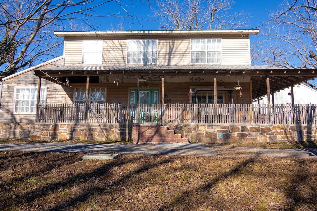 Rustic-style home located on Highway 94 in Rogers, situated outside city limits, on approximately 4.22 acres, offering more flexibility and fewer restrictions. The home features an open living area with vaulted ceilings, a stone fireplace, and abundant natural light, complemented by warm wood finishes throughout. The main kitchen offers ample cabinetry and counter space and flows into the living and dining areas. In addition, a rear area includes an electric cooktop and sink, providing flexible use as a studio or hobby space. A large detached shop measuring approximately 38x48 (about 1,824 sq ft) offers excellent space for storage, workshop, or multiple uses. Covered front porch, mature trees, and a peaceful setting with convenient access to Rogers