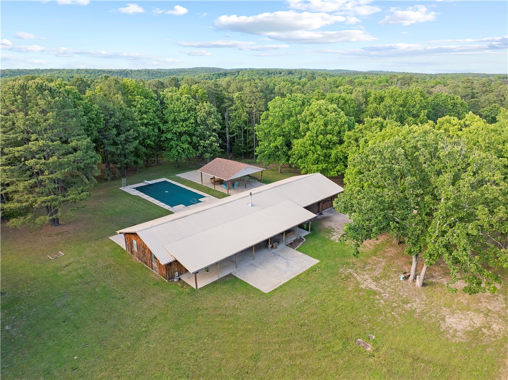 Hidden among the trees on 105 +/- acres, this private and secluded property offers the space, freedom, & versatility so many buyers are searching for. The 3 bed, 2 bath home features a massive kitchen with a large center island, spacious living area with a wood-burning stove for added warmth & character, and a primary bathroom with a whirlpool tub/shower combo. A covered front porch stretches the full length of the home, creating the perfect place to unwind and enjoy the peaceful setting. Outside, you’ll find an in-ground pool, a 70x50 shop with water & electricity, and THREE working wells already in place — opening the door for future homesites, additional construction, or investment potential. Hunt, farm, ride ATVs, or create your own private retreat, all while being just 20 minutes from a marina & boat ramp on Bull Shoals Lake. Properties like this rarely hit the market.