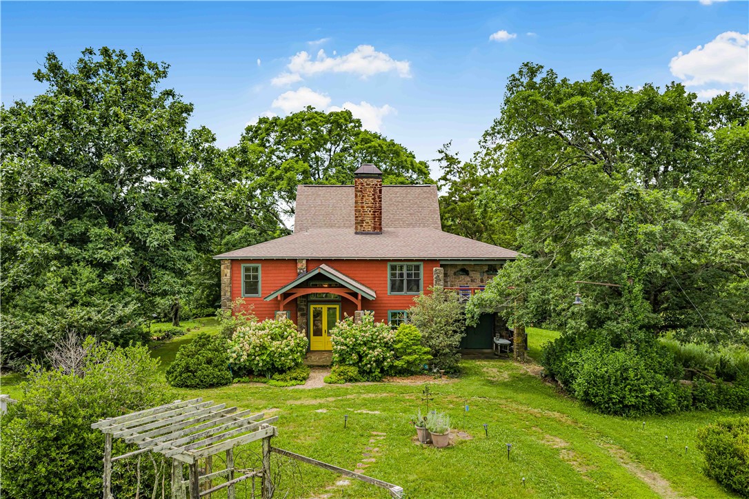 Timeless character and modern updates come together on 69.13 acres in the Arkansas Ozarks. Located about 30 minutes from Fayetteville, 21701 Mount Gaylor Drive offers a peaceful mountaintop setting with wooded acreage and scenic surroundings.

Originally built and updated in 1999, the property includes a 3,348-square-foot main home with 2 bedrooms and 2 bathrooms, along with a separate 1-bedroom, 1-bath native stone guest cottage. The guest cottage features its own kitchen, enclosed porch with a Jacuzzi, and private deck.

Inside the main home, tall ceilings, expansive windows, natural stone accents, and a unique floor plan bring the outdoors in. The upper-level kitchen and living areas overlook the surrounding landscape.

The landscaped grounds include gardens, a lily pond, native stone patios, a fenced garden, and a cedar gazebo. Flowering trees, shrubs, native plants, and perennials attract butterflies, hummingbirds, songbirds, and other local wildlife throughout the season.