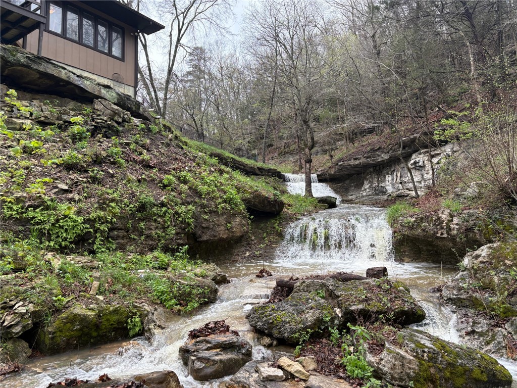Escape to your own private oasis on the North Clifty arm of Beaver Lake and enjoy breathtaking scenery including towering bluffs, stunning waterfalls & 1500' of crystal clear lake frontage. This extraordinary 66.51-acre gated retreat offers a perfect blend of seclusion, natural beauty, & lakeside living. From the comfort of the open concept kitchen/living area of the beautifully remodeled 5 bedroom/2 bath primary home (updated in 2023) you’ll delight in a series of cascading waterfalls flowing just off the back deck, creating a peaceful soundtrack as natural light pouring in from the expansive windows immerses you in the beauty of the surrounding landscape. Exposed beams, vaulted ceilings, & a custom fireplace add warmth & character.  A beautifully finished shop/studio (30x50- built in 2024) includes kitchen, bath, office & additional living spaces showcasing Ozark mountain sunset views. Multiple outbuildings & RV pad include water/electric.  15 min. From Eureka Springs, 55 min. from NWA.