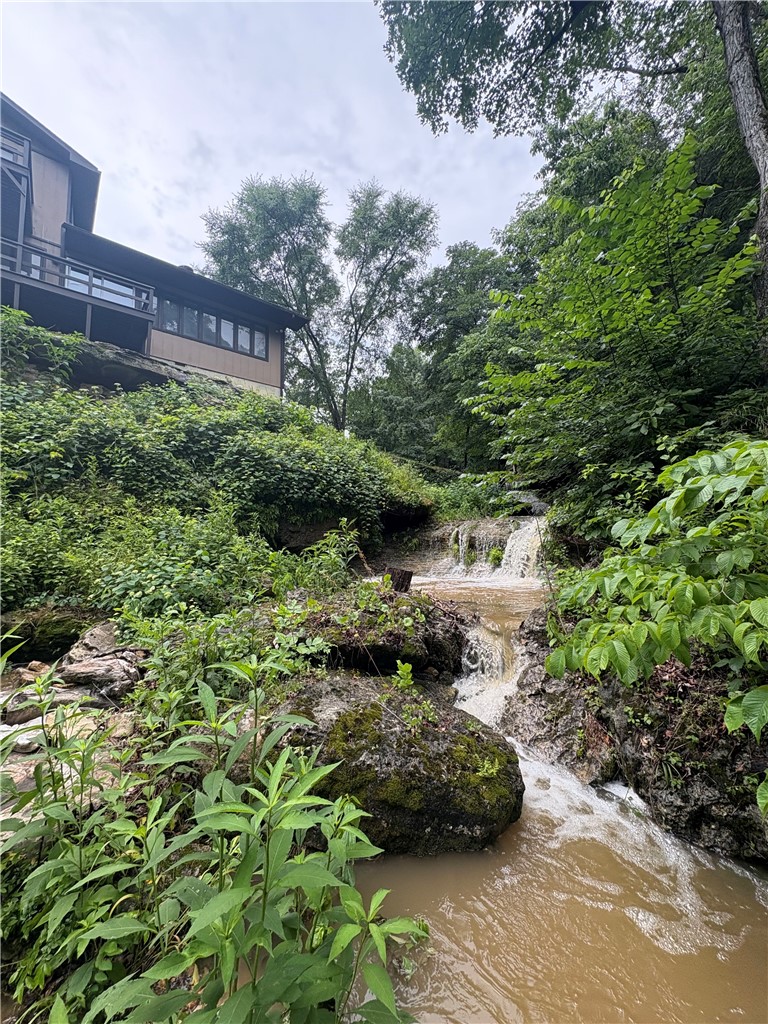 Escape to your own private oasis on the North Clifty arm of Beaver Lake and enjoy breathtaking scenery including towering bluffs, stunning waterfalls & 1500' of crystal clear lake frontage. This extraordinary 66.51-acre gated retreat offers a perfect blend of seclusion, natural beauty, & lakeside living. From the comfort of the open concept kitchen/living area of the beautifully remodeled 5 bedroom/2 bath primary home (updated in 2023) you’ll delight in a series of cascading waterfalls flowing just off the back deck, creating a peaceful soundtrack as natural light pouring in from the expansive windows immerses you in the beauty of the surrounding landscape. Exposed beams, vaulted ceilings, & a custom fireplace add warmth & character.  A beautifully finished shop/studio (30x50- built in 2024) includes kitchen, bath, office & additional living spaces showcasing Ozark mountain sunset views. Multiple outbuildings & RV pad include water/electric.  15 min. From Eureka Springs, 55 min. from NWA.