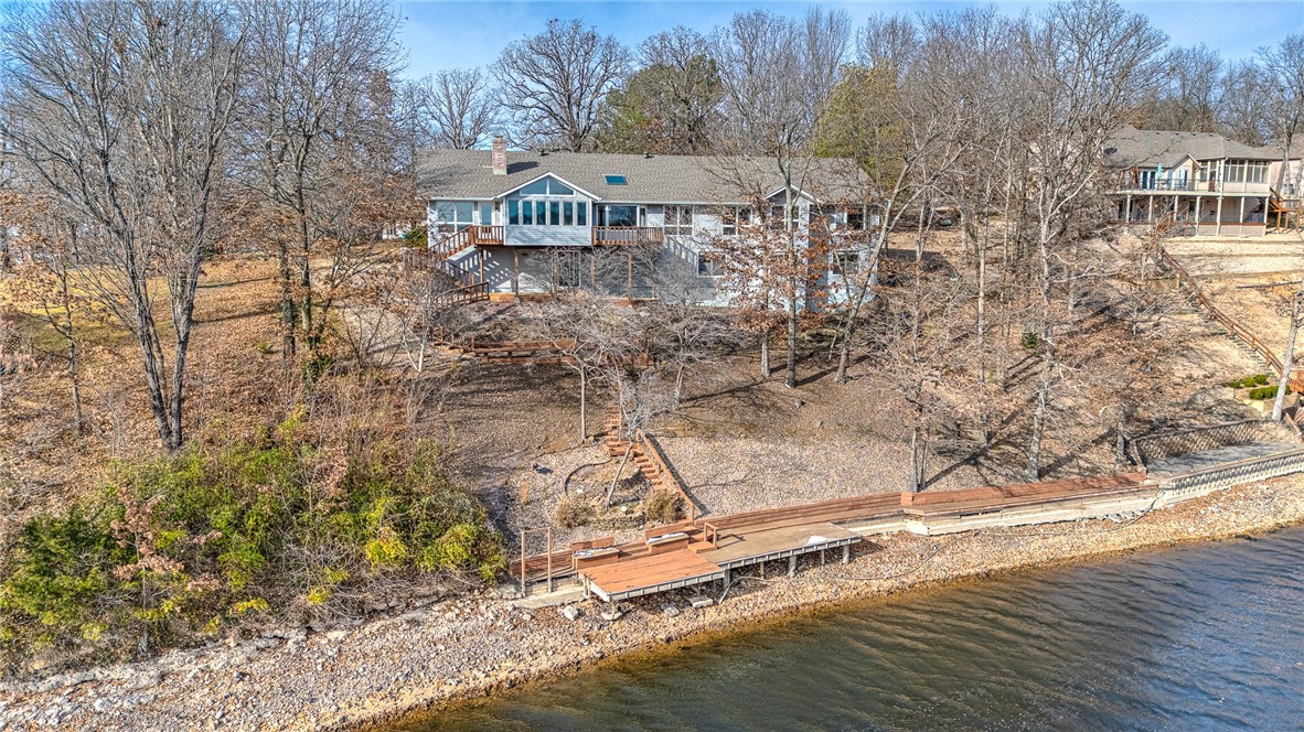 Experience stunning lakefront living on Loch Lomond in this spacious, light-filled home located on a beautiful, quiet street. Featuring floor-to-ceiling windows and skylights throughout, natural light pours into every gathering space. Two expansive sunrooms showcase serene water views year-round. The main level offers exceptional livability with two bedrooms + an office that could easily serve as a third bedroom, along with a formal dining room and two inviting living areas. The lower level extends the living space with a large family room, an additional bedroom, a flex room with endless possibilities, and a walk-out design that brings you steps from the water’s edge. A well-planned, oversize garage includes dedicated golf cart parking, adding convenience for lake and community enjoyment. With ample room for relaxing, entertaining, and hosting, this thoughtfully designed lakefront property offers an unmatched Loch Lomond lifestyle less than 10 minutes from Bella Vista amenities and only 20 minutes from Bentonville.