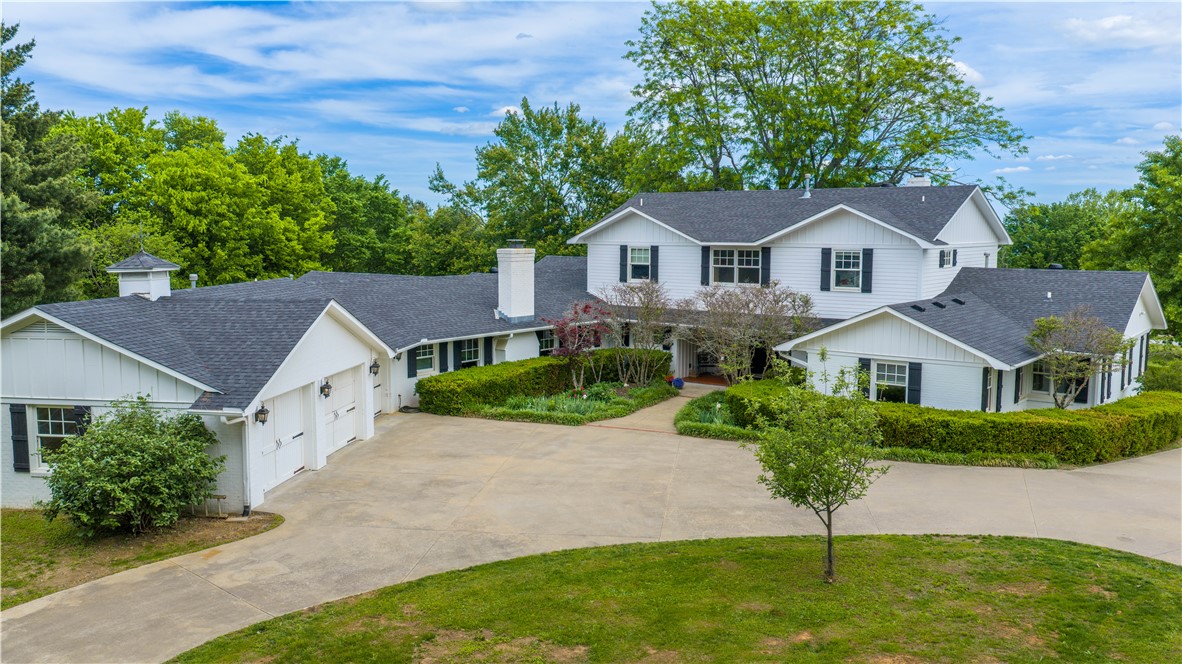 Spacious living meets quiet privacy on Fayetteville’s east side. An expansive family home situated on 2.94 private acres, with a 40’x60’ finished and insulated shop. The 5 bedroom layout features the primary suite and additional bedroom on the main level, with 3 more bedrooms and a bonus space upstairs. Enjoy multiple living areas including two spacious living rooms, and a dedicated study, perfect for everyday living and entertaining. The kitchen showcases rich alder cabinetry, a walk-in pantry, and an effortless flow. Three fireplaces add warmth and character, creating inviting spaces to relax and gather. Step out back to a generous screened-in porch overlooking the private grounds and organic garden. This property offers abundant storage throughout including the 3-car attached garage. Across the circle drive is an impressive 3 bay workshop, perfect for RV parking, and ready for mini split installation. This estate like home offers room for everything, inside and out.