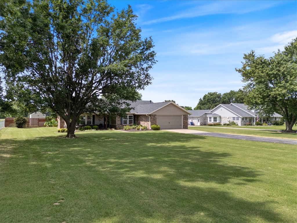 Space, privacy, and convenience come together on this beautifully maintained 2.88-acre property just minutes from I-49, shopping, dining, schools, and the expanding Highway 412 interchange. The open floor plan connects the living, dining, and kitchen areas, creating an inviting space for everyday living and entertaining. A wood-burning fireplace with a blower efficiently warms the main living area. The kitchen features abundant cabinetry, generous prep space, and a pantry. Exceptionally spacious bedrooms offer flexibility for guests or a home office. Outside, enjoy usable acreage, a covered patio, chicken coop, storage shed, and room for gardening, recreation, or hobby farming. The back pasture produces approximately 20 to 30 bales of hay annually, offering income potential. Roof replaced approx. 3 years ago and new heating system installed approx. 3 months ago. Natural gas, public water, two-car garage w/insulated door. Minutes to major employers, healthcare, recreation, and everyday conveniences.
