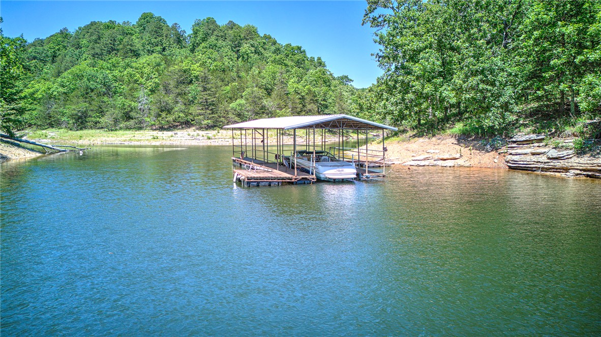 Lakefront retreat on Beaver Lake just 15 minutes from Downtown Rogers dining and entertainment. This distinctive 3 level cabin offers elevated lake living with vaulted ceilings, open-concept design, and expansive wraparound decks on multiple levels for seamless indoor-outdoor living. The upper-level primary suite is a private escape with serene lake views. The lower level features two additional bedrooms, a second living area with wood burning stove, and a bonus room with gun safe ideal for guests or flexible use. A private walking trail leads directly to a 2 slip dock and the clear waters of Beaver Lake, providing rare true lakefront access. Designed for both relaxing and entertaining, this property delivers the ultimate lake lifestyle with space, privacy, and unbeatable proximity to Rogers.