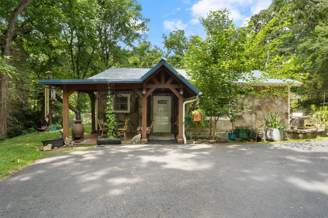 Charming native stone cottage tucked into the woods beside a tranquil wet weather creek on almost 2 acres. This pristine retreat is perfectly situated 2 minutes from the Kings River and about 10 minutes from both Eureka Springs and Berryville. This 2 bed/2 bath cottage has a relaxed estate feeling to it as you drive through the gate and down the winding black topped driveway it reveals the Custom Cottage with a new front patio that is perfect for relaxing and enjoying the natural beauty of the creek and the bounty of local wildlife. Inside you will find a thoughtfully updated home with a seamless floorplan and amazing new Anderson Picture windows for maximizing the calming wooded views & taking advantage of all the natural light. The primary suite with ensuite bathroom and walk in closet is a dream, but wait there is more...a screened in back porch is perfect for sleeping outside on those cool spring and fall nights. Back yard is ready to roll with a greenhouse and a fenced in yard for family and pets. Welcome Home