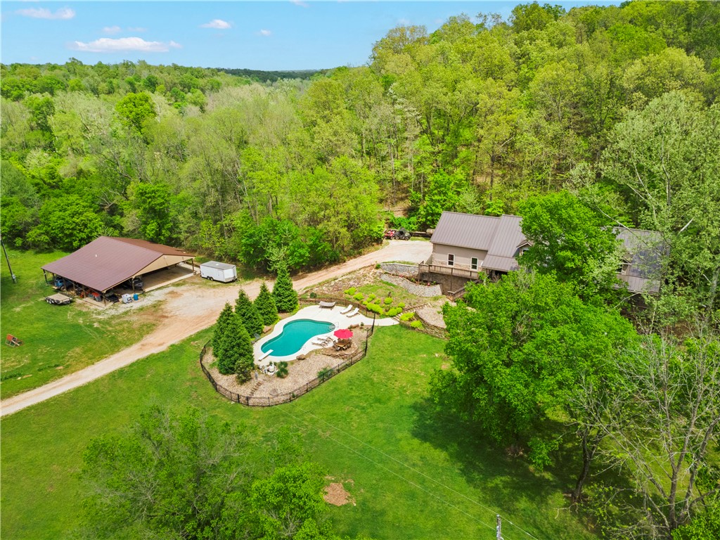 The perfect NWA home -- 30 Acres, Pond, River Access, Tucked Away from it all yet just 20 minutes from Walmart HQ. This renovated 6-bed, 5-bath luxury estate offers the ultimate in privacy with no visible neighbors while remaining just 12 minutes from downtown Rogers. The home features wood flooring throughout, dedicated office, remarkable 500 sq ft bunk room with private entrance (for guests), and fully finished walk-out basement complete with bedroom, full bath, second laundry, and theater room. The gourmet kitchen showcases a 48" GE Monogram range with air fryer, quartz countertops, custom soft-close cabinets, and dual sinks with disposals. The main suite has a heated shower, floor heaters, dual closets, and custom vanities. The property's 50x50 shop includes heated/cooled office, walk-in cooler, RV hookup, and bathroom. Enjoy the pool, spring-fed pond, half-mile walking trail and fenced pasture. Fun features include whole-house spring water filtration, high-efficiency wood stove, and low utility bills!