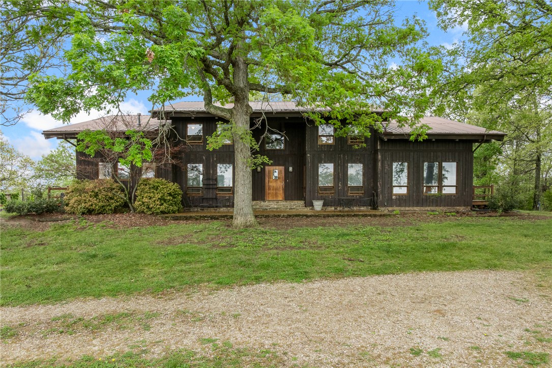 Tucked into the breathtaking Boston Mountains near Huntsville and Osage, this rare Ozark retreat offers unmatched privacy, character, and natural beauty. The stunning 6,434 sq ft contemporary home features 4 bedrooms, 4.5 baths, soaring 26’ ceilings, rich oak and walnut finishes milled from the property, and a dramatic two-story fieldstone fireplace. A finished walk-out basement with workshop connects through a one-of-a-kind stone tunnel to a 3-car garage. A charming 544 sq ft guest cabin with loft, full kitchen, spacious porches, and 2-car carport provides ideal guest or rental space. The 32x50 barn includes electric, 3 stalls, tack room, and pens. The land showcases rolling pasture and timber, fenced and cross-fenced, with 3 ponds, a natural spring, trails, vineyard, and garden space. Shared deep well, mineral rights
convey. Just 15 miles to the Buffalo National River—perfect for a private estate, recreation, or investment opportunity.