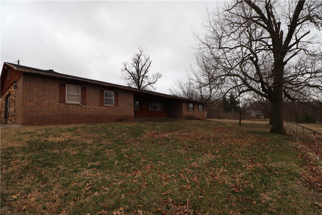 Brick home on a hill with 4.89 acres and a beautiful view waiting to be updated. Excellent location in Elm Springs just off Hwy 112. Huge 40 X 60 shop building with roll up doors and 30 X 49 barn with built in stalls. Pipe fencing surrounds most of the property and there is a pond. Great value add opportunity in a growing area