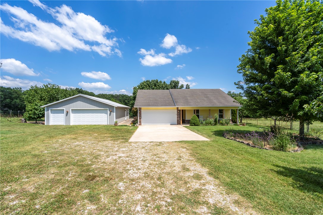 Country living at its finest & all on a paved road! Welcome to this charming 3BD, 2BA, 1368SF home. The 5.29 acres of gently rolling pasture provides plenty of room for livestock, gardening or simply enjoying the peaceful surroundings. Outside, you'll find raised garden beds, a koi pond, a pergola w/access from the primary bedroom, & 32'x40' insulated shop w/10'x32' office in the back-perfect for a home business, hobbies, or extra storage. Inside, you'll find a wood-burning fireplace, Pergo flooring throughout the main living areas, tile in entry/baths & a spacious primary suite w/tray ceiling. Eat-in kitchen has butcher block counters, SS appliances & farmhouse sink. HVAC system was replaced in 2023 w/transferrable warranty. Convenient access to Bella Vista golf courses, walking/biking trails & everyday amenities. 5 min walk to the Back 40-The Ledges trail. 8 min to Pea Ridge/15 min to Bentonville/10 min to Bella Vista. No shoes have ever been worn in this home (please respect, wear provided booties or remove).