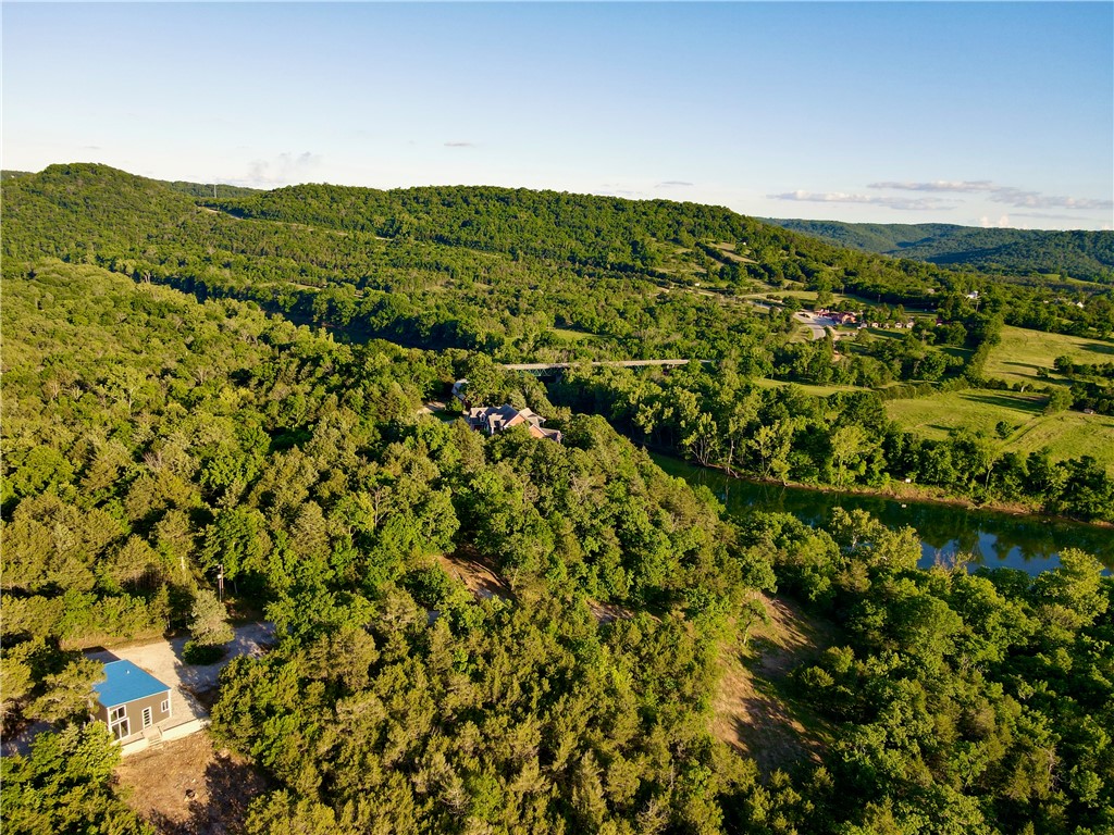 Rarely does a White River property offer this level of infrastructure,
natural beauty, and future potential. This 18.75+/- surveyed unrestricted
tract features approximately 1,036 feet of usable White River frontage
with direct kayak access from the bank. A custom 24’ x 35’ all-steel
building with steel exterior and interior studs offers approximately 1,100
square feet with loft space on a reinforced 6-inch concrete slab, plus a
pull-through garage for boats, UTVs, and equipment. Improvements
include a newly drilled 835-foot well into the Roubidoux aquifer
producing 60 GPM, installed septic, new 200-amp electric, trenching
and sleeving for additional electric service, and water and septic lines
run to two additional cleared build sites. The property also features a
year-round spring, wet weather creek, waterfall, UTV trail to the river,
and south-facing terrain with river views. Located 7 minutes to Beaver
Lake Dam and 15 minutes to Eureka Springs.