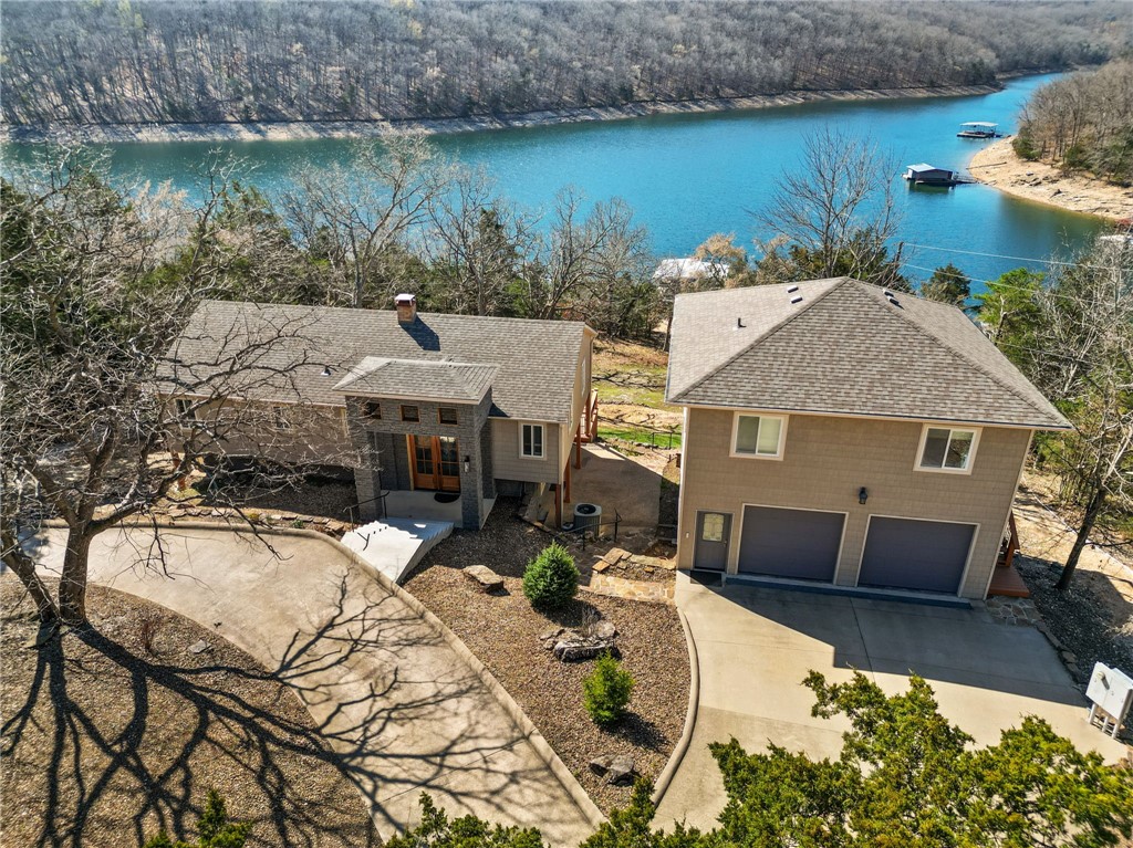 Your lake life needs this lake front with a walk to your private boat dock on Beaver Lake just south of Point 2 on the Indian Creek arm.  A brand new entry with elegant 8 foot doors and new concrete steps leading to a bright space with lake views from almost every window in the house.  Custom cabinets and clean decor ready to customize.  The two-car garage includes a shelter/wine cellar underneath and a luxurious apartment above with its own large deck.  A two slip private dock with boat lifts, swim deck and a jet-ski landing promise memories of every pretty summer.  Come and live in this peaceful, quiet lake neighborhood.  Roof shingles and gutters are all new in 2024, and hot-tub and all appliances convey with this home.