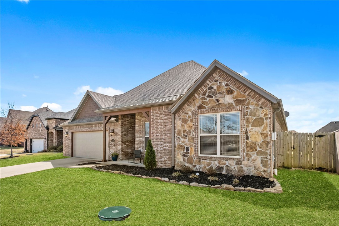 $6,500 lender paid credit to qualified buyers! Right in the sweet spot of NWA, this 4-bed, 2.5-bath home in Marbella is sure to dazzle with brand new wood floors, fresh paint, new primary shower and a prime location in the middle of everything NWA has to offer. The attractive rock & brick exterior is largely maintenance-free, sparing you the repainting cycle that plagues many nearby neighborhoods. The entry opens into an open-concept living & dining area anchored by a stacked-stone gas fireplace. A powder room off the entry, a dedicated laundry room with ample cabinetry and counter space, and a pantry! The kitchen features granite countertops, bar seating for four, and an eat-in area large enough for the biggest gathering table you've got. The primary suite impresses with a vaulted ceiling and a 5-piece ensuite with his-and-hers closets. Out back, a massive covered patio flows seamlessly from the living area into a landscaped yard with irrigation and installed drainage.