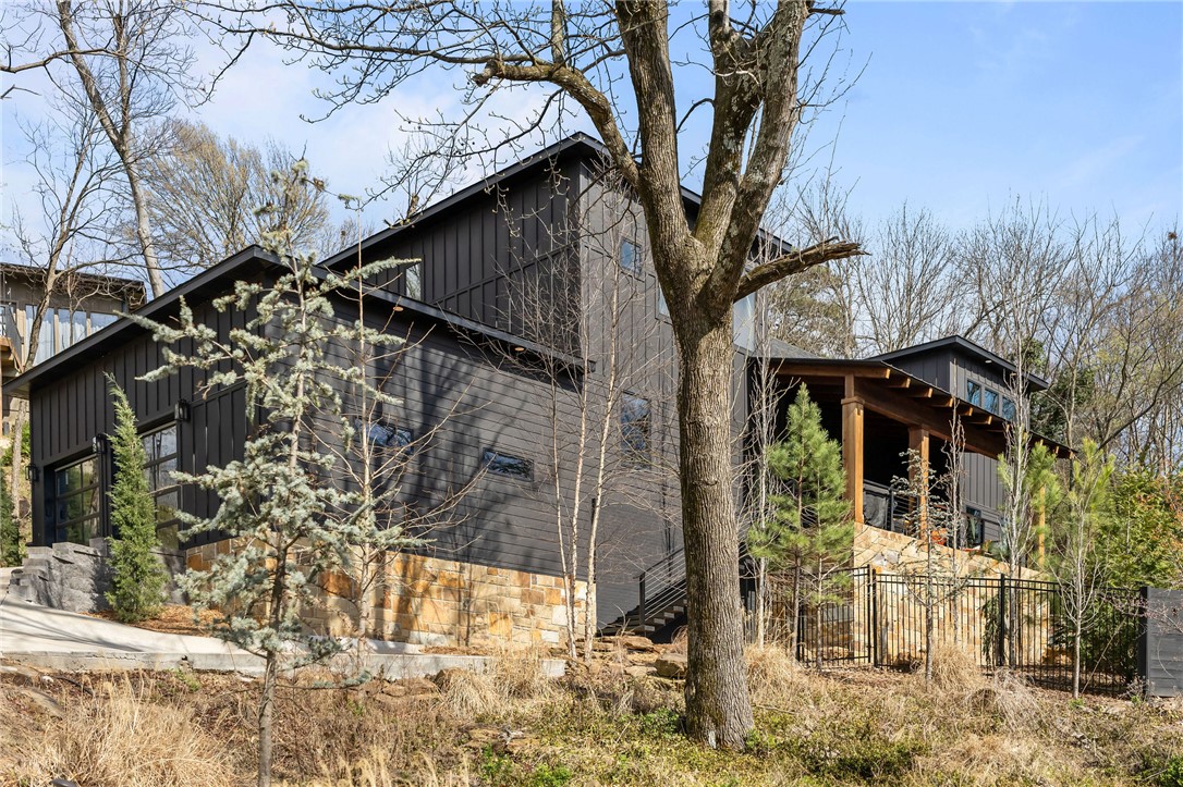 Modern Custom Home designed & Built by GD Consultants in 2022. With 4 beds, 3 baths, plus an office, and covered porches that feel like a secluded escape, this home blends modern design, luxury finishes, in a rare natural setting. Experience refined modern living in this stunning custom home. A bold mountain modern exterior pairs dark siding and stone with warm wood accents and a large elevated front porch.

Inside, the home lives like a private retreat nestled on Mount Sequoyah—perched above the landscape offering seasonal views of downtown Fayetteville & Old Main. A peaceful, treehouse-like feel just ½ mile from Dickson Street.

The light-filled, open-concept interior features soaring cathedral ceilings, oversized windows, a dramatic floating staircase, and European White Oak floors. The kitchen boasts high-end quartz, stain-grade cabinetry, a wine closet and a large island perfect for entertaining.