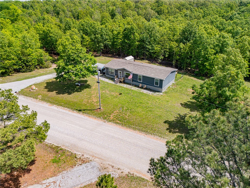 Tucked into the gentle, rolling landscape, this 2022 manufactured home sits on five acres that balance open, cleared space with the natural privacy of established woods. The lot is level enough to use and wooded enough to feel like your own little corner of the Ozarks. No zoning. No restrictions. Just room to breathe, grow, and live the way you want. Inside, the open floor plan keeps things easy—bright, functional and comfortable from the first step through the door. 3 bedrooms and 2 baths give you the space you need without anything to spare. Set on a permanent foundation with full skirting and underpinning, this home is as solid and move-in ready as it looks. But the real draw? Step out onto the open deck and let the quiet settle in. A 12' x 8' storage shed keeps your tools and gear, and the sale conveys a 1953 Ford Jubilee tractor,two TVs, an outdoor table and chairs, a walk-behind weed-eater, and a generator. Everything you need to settle in and start enjoying it immediately.