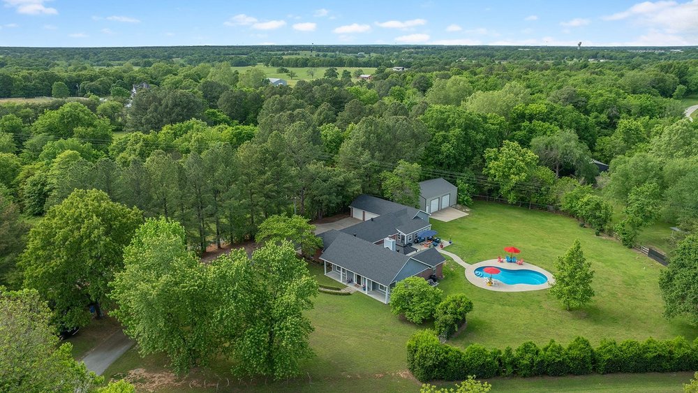 Updated 2809 Sq. ft. home on beautiful 1.5 acres. This unique home offers an in-law suite/family room with full kitchen and dining, walk-in closets and a separate HVAC system. The kitchen in main part of home has new quartz countertops in 2025. Hardwood floors, remodeled master bath with carrera tile, quartz countertops and a Jacuzzi tub. This home also features a 3 car garage, a 30x40 shop building built in 2021, new architectural roof in 2023, a sunroom, new 20x20 gazebo and an outdoor heated pool built in 2021. The glass enclosed extension to the home provides natural light and views of the outdoors. The 1200 sq. ft. shop building has a walk-in door & 2 overhead doors high enough for motor homes and other recreational vehicles.  Within minutes of schools, shopping, restaurants and Interstate 49.