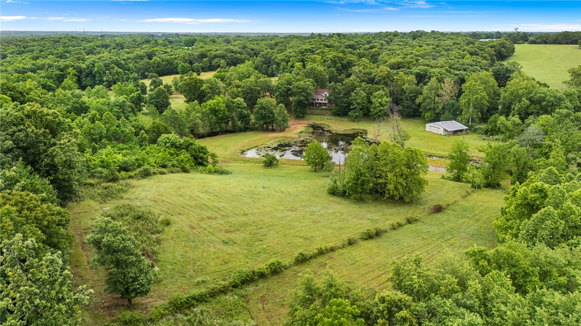 Tucked away on 30 breathtaking acres just minutes from Centerton, this one of a kind property blends natural beauty, privacy, activities and convenience. A spring-fed creek, 1+ acre private mini lake, fruit trees, blackberry bushes, and wildlife create a true retreat that you will be begging to get back to every day. The home is spacious featuring 5 bedrooms and 3.5 baths, stunning stone fireplace, accessible bathroom on the main level, huge entertainment area plumbed for a 2nd kitchen, and you can't forget the multiple balconies with views. Boasting an oversized 3 car garage with additional storage areas adding an additional 548 square feet that's not accounted for in the listing square footage. The Trail of Tears went through this property allowing the opportunity to come across artifacts while on your evening walk, listening to the birds, or fishing in your stocked mini lake. This place is an outdoorsman's paradise. If interested in any of the farm equipment it could be yours!