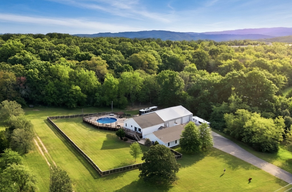 LIMITLESS OPTIONS FOR FAMILY, INVESTORS, AT HOME BIZ OR EVENTS AND 6 MINS TO THE UNIVERISTY OF ARKANSAS! This pristine land & unique tri-level home offers a heated pool & hot tub, sustainable green living w/ a geothermal HVAC system, all new Low-E windows, exterior security sys., brand-new roof and all newly updated appliances + multiple living spaces, 2 kitchens & laundry on each floor. Upper level has living area w/ dual-oven kitchen, 3 bed & 2 bath. Mid level has 3 bed, 3 bath, kitchenette + direct access to deck & pool. Lower level is ideal for entertaining or multi-gen living w/ tall ceilings, kitchen, theater, laundry & bath. Outdoor oasis w/ pool, wrap-around deck & hot tub. Perfect for relaxation & gatherings, the impressive theater room is perfect for game days & movie nights. This isn’t just a home, it’s an opportunity. A 2,400 sq. ft., 3-Bay, climate-controlled shop is a dream for a biz owner, car-enthusiast or artist w/ 10 ton car lift, compressed air plumbing, welding setup, 1/2 bath + pickleball court