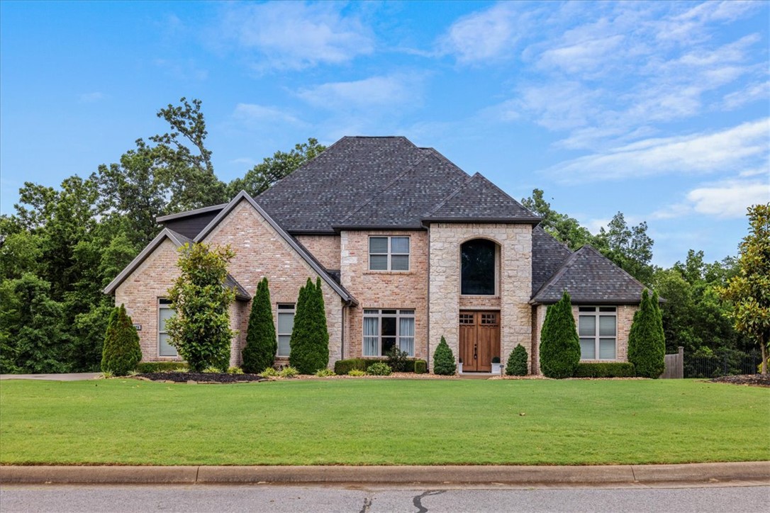 Experience the prestige of Versailles from this exceptional custom home situated on 1.84 private acres. Offering 4,966 square feet of living space, this home balances elegance, comfort, and versatility. The chef’s kitchen is the heart of the home, featuring two oversized islands, top-of-the-line appliances, abundant cabinetry, and ample space for entertaining. The open-concept layout flows into a cozy living room with a gas fireplace, while a second living area with its own gas fireplace provides additional space to relax and gather. The main level includes a luxurious primary suite and an en-suite guest bedroom, ideal for guests or multi-generational living.  Upstairs, you'll find a spacious lounge opening to a private patio and a media/flex room offers endless possibilities to suit your needs.  Enjoy luxury living on a quiet cul-de-sac with convenient access to Northwest Arkansas' major employers, top-rated schools, dining, shopping, and all the amenities the region has to offer