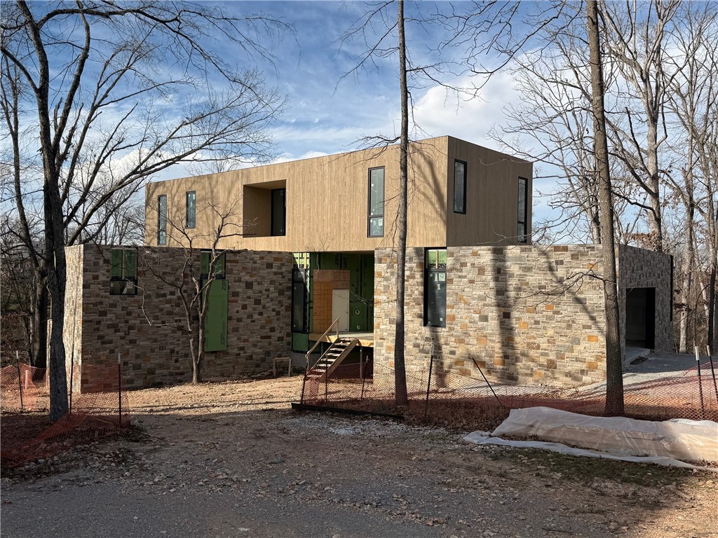 Welcome to Nelagoney Glen — six-home development sharing 9 acres in downtown Bentonville that marries Ozark character with modern luxury. This 2026 contemporary masterpiece by Modus Studio spans nearly 4,000 sq ft on a tranquil and private half-acre lot. Step inside to rich, bold Ravine finishes that set a tone of depth and elegance: darker accents, moody tones, dramatic contrast. Outside, this home backs directly to Park Springs Park. From your primary suite, you’ll enjoy private, wooded views over the spring into the forest beyond, just nature framing your windows. The larger flex room with its attached full bath gives you serious versatility: use it as a guest suite, gym, or home office. Every architectural detail — from large windows and optional green-roof features to natural Kentucky Blue Stone and Accoya wood siding — is built for quality and harmony with the land. If you want to live downtown but feel like you’re secluded in the woods, this is your opportunity.
