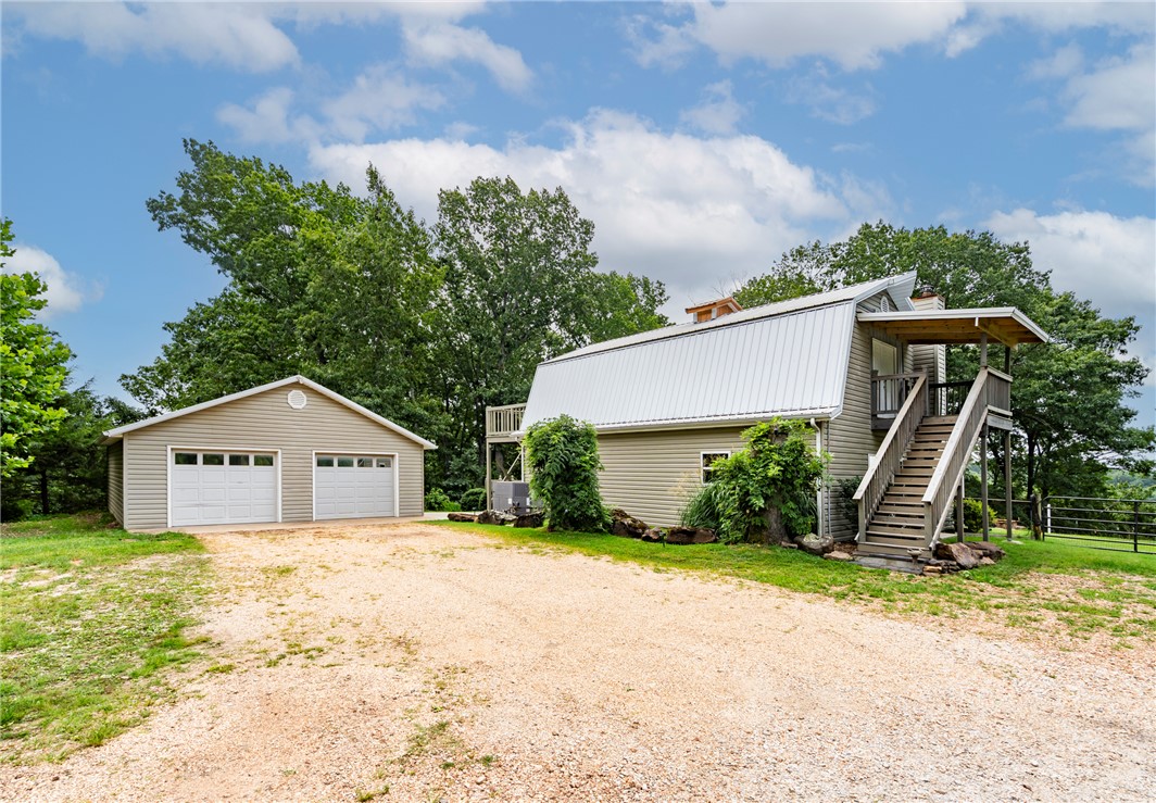 Escape to peaceful country living with breathtaking Beaver Lake views.  This beautiful 2BD/1BA home offers 1,620SF of living space surrounded by 4.98 acres.  Inside, you'll find custom oak cabinetry, real hardwood flooring throughout the main living areas & tile in the wet areas. Both bedrooms feature private decks overlooking Prairie Creek & walk in closets.  One bedroom has access to ground level w/ private stairs off deck. The lower deck has been reinforced & pre-wired for a hot tub. Covered back porch is perfect for morning views of the lake w/ coffee. The property is packed w/ outdoor amenities, including a charming frog pond, greenhouse, garden areas, fire pit/conversation area, detached/cooled 2-car garage w/ convenient attic storage & 8x16 storage building for additional space. ADT solar panels mean only a meter fee for electric! Rural water, propane & septic. Whether you're looking for a full-time residence or weekend retreat, this property offers a perfect blend of comfort, functionality & natural beauty.