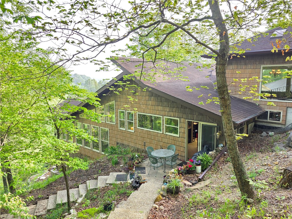 Perched on 13 m/l beautifully fenced acres overlooking the crystal-clear, year-round waters of Crooked Creek, this extraordinary 2BR/2BA home offers 2,358sf of privacy, character, and breathtaking Ozark Mountain beauty. Artfully & lovingly designed and exceptionally built, the home welcomes you through a charming atrium entrance and opens to soaring beamed ceilings, walls of windows, and stunning views from nearly every room. Wake each morning to the sight of the valley, the sounds of songbirds and the flowing creek from the spacious bay windows in the primary suite and from your private balcony.

Inside, you'll find abundant storage, a butler's pantry, extra closets, and unique architectural details throughout. Outside, a storm cellar, storage building with enclosed well house, and a private limestone bluff trail lead down to your own creekside picnic area—perfect for family gatherings, fishing, or simply enjoying the beauty of Crooked Creek.