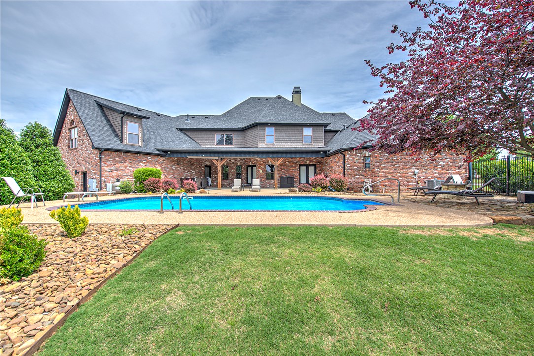 DREAM SETTING IN THE HEART OF ROGERS! This custom-built 5BR/4.5BA home sits on a beautifully landscaped 0.61-acre corner lot with a circle drive and 4-car garage. The private backyard retreat boasts a resort-style saltwater pool, lush grounds, and refined entertaining spaces. The stunning interior showcases timeless elegance, highlighted by rich wood floors, soaring cathedral ceilings, exquisite millwork, and classic wainscoting that add depth, character, and enduring charm. The chef’s kitchen impresses with 2 dishwashers, large island with prep sink, gas cooktop, and double ovens. Two living areas, wine cellar, and wet bar add to the appeal. The main-level primary suite features a spa-like bath with steam shower, soaking tub, and dual closets, plus an attached executive office & a cozy reading nook that walks out to the covered patio & pool. Upstairs hosts 4 bedrooms, 2 baths, and a large bonus room with private garage access—ideal for a teen suite, gym, or media room. Minutes to Pinnacle Hills & downtown Rogers!