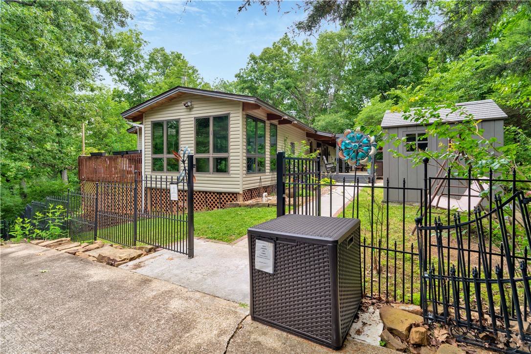 This charming, custom-built, one-owner home is tucked among the trees, offering privacy while remaining convenient to highway corridors, schools, grocery stores, restaurants, and shopping. Large windows fill the home with natural light, while beautiful wood bookshelves and native stone fireplaces add warmth on both the main and lower levels. The main level features an open-concept living, dining, kitchen, half bath, and sunroom area, plus an office/bedroom and the primary bedroom/bath. The lower level includes a second den with fireplace, two bedrooms, one bathroom, and a storage/workout room. Additional highlights include a new roof in 2026, Pella windows, two storage sheds, and solar panels & hot tub that convey with sale. This home is an ideal fit for buyers seeking a peaceful, secluded setting with everyday conveniences nearby.