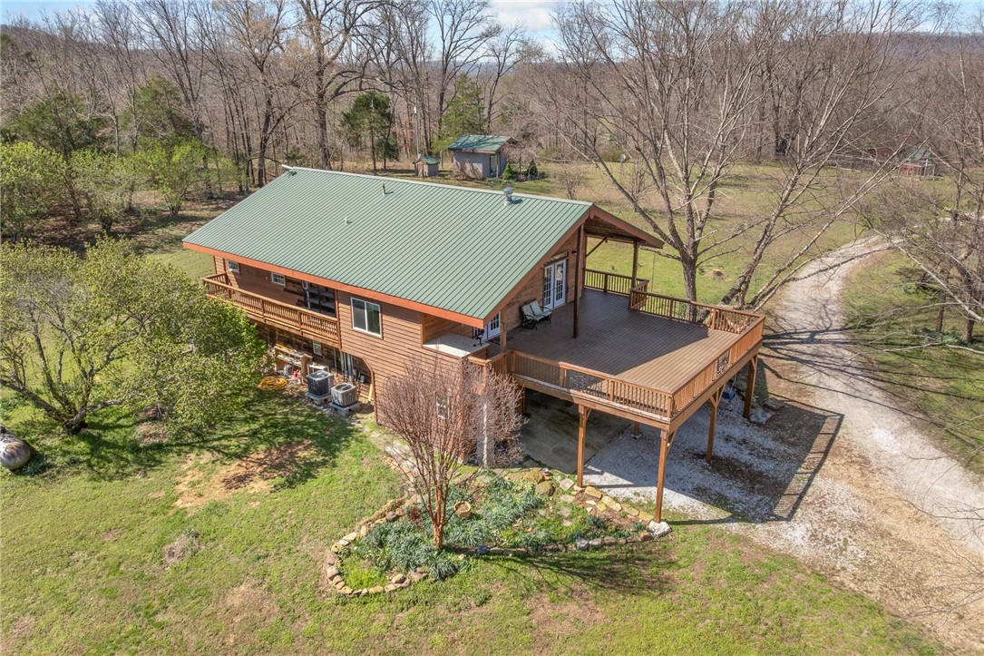 Escape to your country paradise on almost 42 acres of scenic Arkansas countryside.  This property offers 2,894 square feet, running waters on two sides, over 900 square feet of front deck for entertaining, multiple insulated outbuildings and a park like setting filled with fruit trees and flowers everywhere.  All of this creating a serene landscape year-round.  Inside the home you will find two distinct living floors, perfect for multi-generational living or mother-in-law quarters.  The centerpiece of the second floor is an Italian imported wood stove that adds style and functionality to the common space.  Spacious bedrooms with great windows produce an abundance of natural light for picture perfect views of your surrounding  landscape.  This property has 4 different outbuildings (totaling 4,715 square feet) providing its new owner with plenty of places to park all of their things along with extra storage for toys and tools that you will need to explore your 42 acre playground.