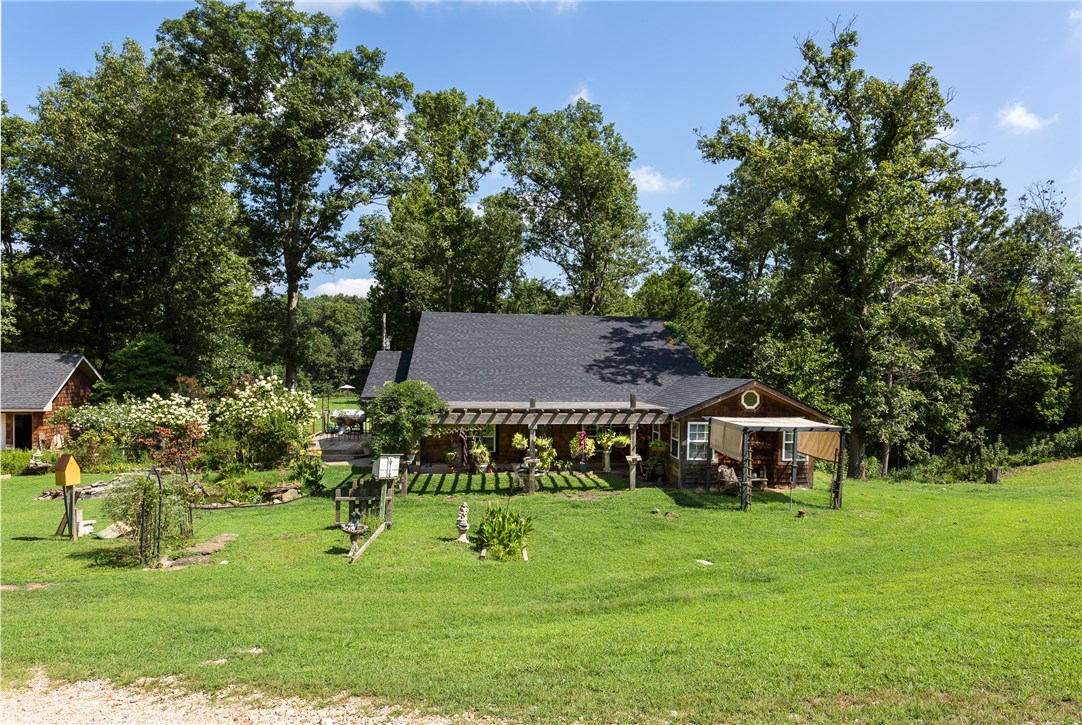 Properties like this are hard to find in NW Arkansas. Unique Saltbox style home built in 1988, 3 br/2ba, 4 car detached garage, storage building, shop or Large 2600 sq. ft. Barn w/loft & woodburning Stove. Beautiful setting, 24.5 acres, part open & partially wooded and has a Wet weather creek. Watch the deer, enjoy gardening, horses, cattle, outdoor & indoor living. So many amenities! Brick LR flooring, 2 living areas, Kitchen has lg walk-in pantry, new wood flooring, appliances, lighting & more