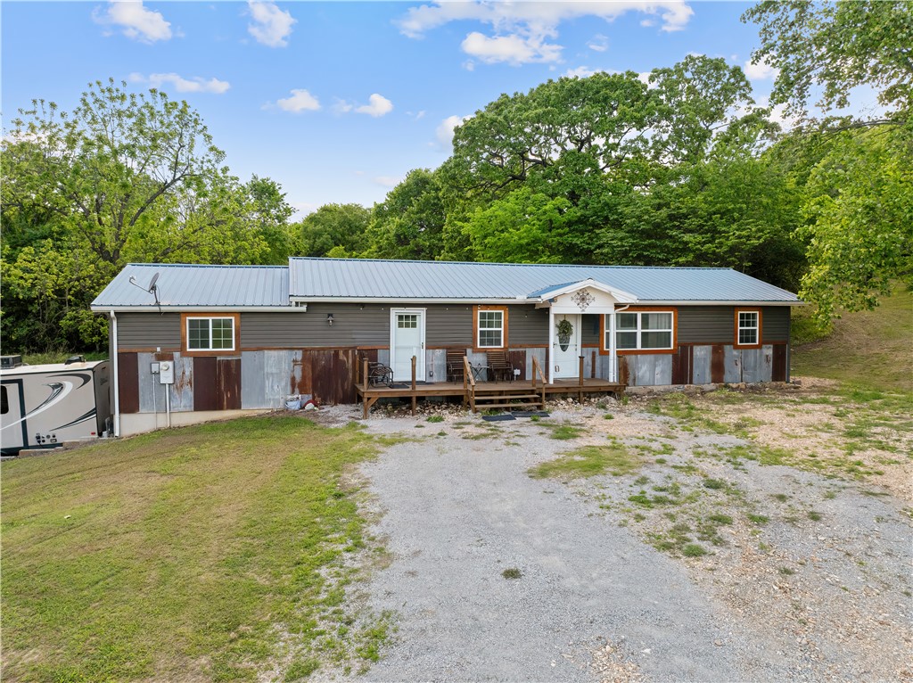 Tucked into the rolling hills just minutes from Bull Shoals Lake, this 3-bedroom, 2-bath home on 4 acres blends comfort, functionality, & country living. Updated kitchen features quartz countertops, black stainless appliances, custom island, farmhouse sink, & gathering space. Spacious primary suite offers a large custom walk-in shower, while the walk-out basement adds flexibility for storage, hobbies, or extra living space. Home includes central heat & air with propane backup, fiber optic internet, water softener, new 50-gallon water heater, & generator wiring. Outside features a fenced garden spot, fruit trees, blackberries, walnut & pecan trees, RV hookup, tree house, & income-producing Highway 7 frontage billboards. Outbuildings include a 16x18 machine shed, 24x20 concrete garage with lean-to, & 16x18 storage building with attached bay. Just 5 minutes from Bull Shoals Lake & 12 minutes to Sugarloaf Harbor Marina.