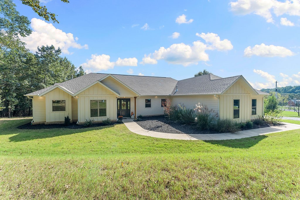 Set on 5 acres, this 1-story 2022 build blends everyday comfort w/ sophisticated design. Featuring 3 beds, 2.5 baths & an office, the thoughtful split floor plan balances open-concept living w/privacy, while an oversized entryway welcomes you into the sun-filled living spaces. Large windows throughout flood the home w/ natural light, accentuating the modern finishes. At the heart of the home is the kitchen, complete w/ a 10' island w/ bar seating, walk-in pantry, SS appliances & a 6-burner gas cooktop. A dry bar enhances the dining area, while french doors open to a covered patio, perfect for entertaining. The living room features vaulted ceilings, a gas fireplace & a custom oak mantle. The primary suite is a true retreat w/ a private patio. The ensuite bath features a soaking tub, walk-in shower, dual vanity, & generous walk-in closet. With private lake access & a sandbar, 2 patios for year-round enjoyment of breathtaking views, this home perfectly blends luxury and functionality in a serene lakeside setting.