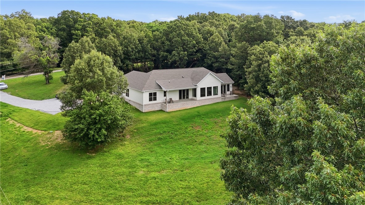 Set on 5 acres, this 1-story 2022 build blends everyday comfort w/ sophisticated design. Featuring 3 beds, 2.5 baths & an office, the thoughtful split floor plan balances open-concept living w/privacy, while an oversized entryway welcomes you into the sun-filled living spaces. Large windows throughout flood the home w/ natural light, accentuating the modern finishes. At the heart of the home is the kitchen, complete w/ a 10' island w/ bar seating, walk-in pantry, SS appliances & a 6-burner gas cooktop. A dry bar enhances the dining area, while french doors open to a covered patio, perfect for entertaining. The living room features vaulted ceilings, a gas fireplace & a custom oak mantle. The primary suite is a true retreat w/ a private patio. The ensuite bath features a soaking tub, walk-in shower, dual vanity, & generous walk-in closet. With private lake access & a sandbar, 2 patios for year-round enjoyment of breathtaking views, this home perfectly blends luxury and functionality in a serene lakeside setting.