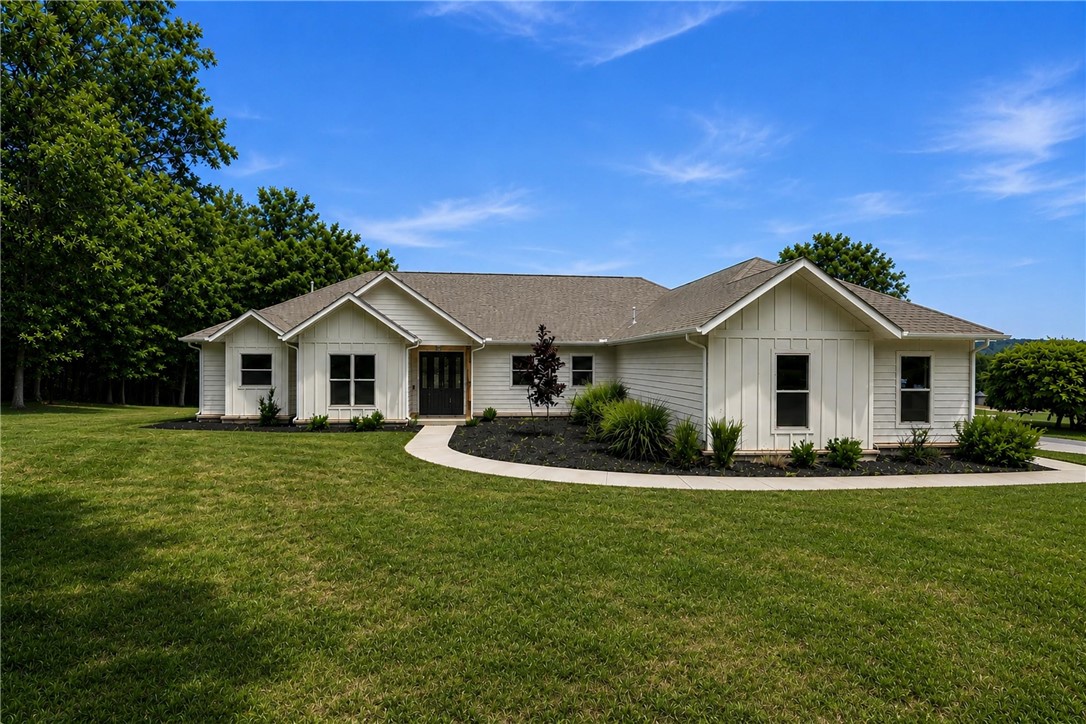 Set on 5 acres, this 1-story 2022 build blends everyday comfort w/ sophisticated design. Featuring 3 beds, 2.5 baths & an office, the thoughtful split floor plan balances open-concept living w/privacy, while an oversized entryway welcomes you into the sun-filled living spaces. Large windows throughout flood the home w/ natural light, accentuating the modern finishes. At the heart of the home is the kitchen, complete w/ a 10' island w/ bar seating, walk-in pantry, SS appliances & a 6-burner gas cooktop. A dry bar enhances the dining area, while french doors open to a covered patio, perfect for entertaining. The living room features vaulted ceilings, a gas fireplace & a custom oak mantle. The primary suite is a true retreat w/ a private patio. The ensuite bath features a soaking tub, walk-in shower, dual vanity, & generous walk-in closet. With private lake access & a sandbar, 2 patios for year-round enjoyment of breathtaking views, this home perfectly blends luxury and functionality in a serene lakeside setting.