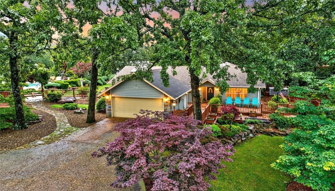 This well-appointed Fayetteville home offers privacy, comfort, and convenience on over an acre just minutes from amenities. The 3,357 sq ft residence features three bedrooms, three and a half baths, updated hardwood floors throughout, a newer HVAC system, whole house generator, and a two-car garage.
Highlights include a wrap-around porch, professional landscaping, sunroom with skylights, and a fireplace in the main living area. The kitchen boasts granite counters, stainless appliances, custom cabinets, and a breakfast bar adjacent to a formal dining room. The main floor master suite provides hardwood floors, ample closet space, and a bath with dual vanities, soaker tub, and walk-in shower. Two additional bedrooms are suitable for guests or flexible use. Outdoor amenities feature a self-cleaning sport pool, hot tub, large patio, pergola with lighting, greenhouse, lush yard, and private guest house with its own bedroom, bathroom, kitchen, and living area. Appliances and pool equipment are included.