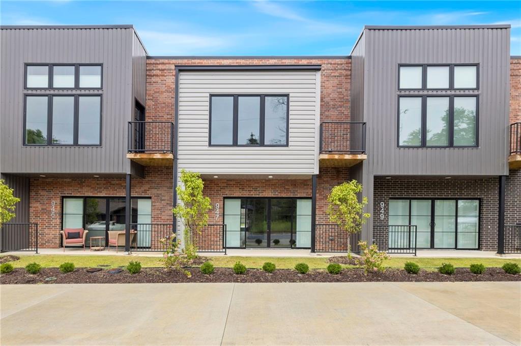 Experience modern living at SoMa Terrace, ideally located directly across from the new Walmart Home Office Campus and just a short walk to 8th Street Market, The Momentary, restaurants, coffee shops, and the Razorback Greenway. This stylish two-story condo lives like a townhome and offers an open-concept floor plan with a private attached garage, spacious living area, and an impressive 4-panel sliding glass door leading your patio area. The kitchen features white oak and white cabinetry, quartz countertops, a striking black tile backsplash, a large island with seating for four, and a full appliance package including a refrigerator plus full-size washer and dryer. Upstairs, the primary suite offers a private balcony, walk-in closet, and spa-inspired bath with dual showerheads. Thoughtful designer finishes, professionally landscaped grounds, and an exceptional walkable location make this a standout opportunity in Bentonville.