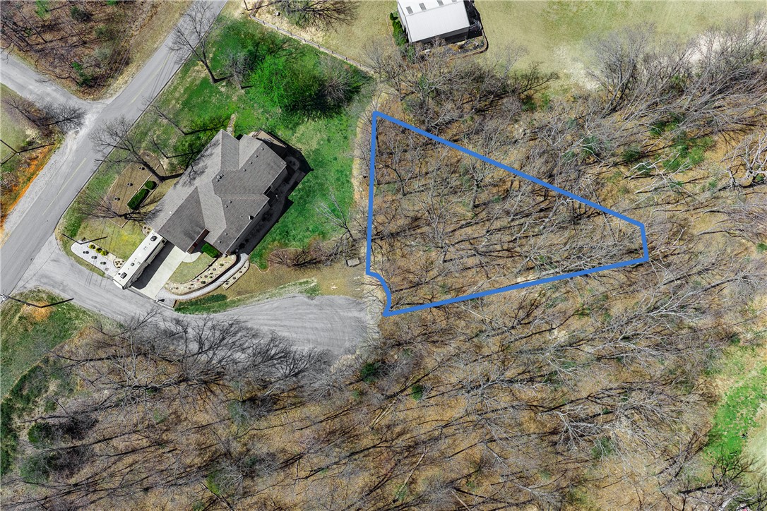 Tucked at the end of a peaceful cul-de-sac on Askew Lane, this 0.24-acre wooded lot in Bella Vista's Croydon subdivision is your chance to build something special. The gently sloping, tree-lined terrain provides privacy and natural charm at an incredibly accessible price — just $19,000 with annual taxes of only $53. Electricity runs to the street, public water is available, and a private septic system will be needed. As a Bella Vista POA member at just $16/month, you'll enjoy an extraordinary lifestyle: 7 golf courses, 7 private stocked lakes, 100+ miles of hiking and biking trails, swimming pools, tennis courts, fitness centers, a gun range, and parks throughout the community. This is NW Arkansas living at its finest.