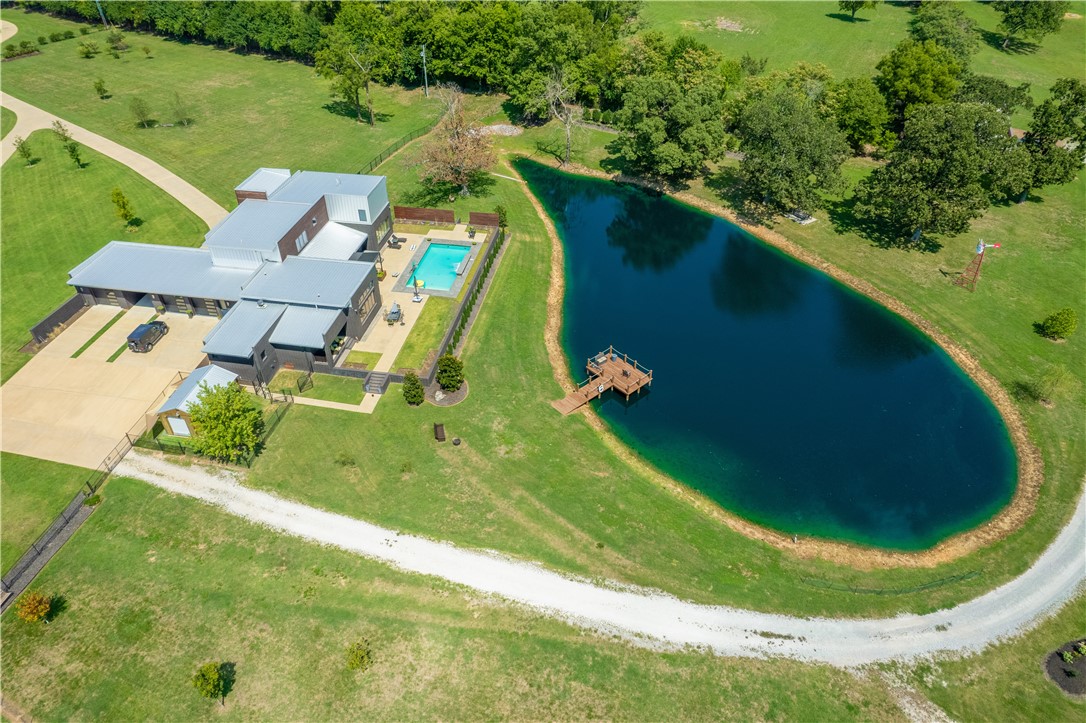 Stunning Modern Estate property. Approx. 9.43 fenced in acres with gated smart entrance. Builder says this house could not be built for this price today. Two minutes from 112/ 612 to interstate, 13 min from Tyson head quarters, and 7 minutes to hospital, WM, Starbucks, or Sam's. Raised, heated saltwater pool overlooks three quarter acre stocked pond with dock. Storage barn by gated entrance. Main house was completed in Aug. 2017 has chef's kitchen with Brazilian quartzite and large walk in pantry. Two fireplaces and a staircase with inlaid walnut. Two ground floor masters. Multiple entertaining areas and soaring 14 ft. ceilings. Natural light floods in with the abundance of large windows. This home is a must see.