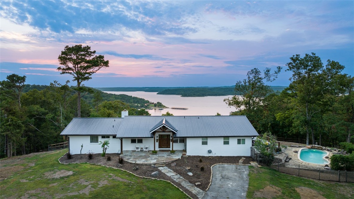 The Seller is offering a $30k Allowance towards Rate Buy Down, Landscaping, or Upgrade of your choice! This stunning 3395 sq ft home, spread across two levels, offers the perfect blend of comfort & luxury. Nestled on 9 acres w/breathtaking views of Beaver Lake, this residence is a serene retreat from the hustle & bustle of everyday life. Inside, you’ll find 4 spacious bedrooms & 3.5 baths, perfect for accommodating family & guests. The open floor plan seamlessly integrates the living, dining, & kitchen areas, creating an inviting space for entertaining & relaxation. Step outside & discover your own private oasis. The expansive deck is ideal for hosting gatherings or simply enjoying the tranquil surroundings. Take a dip in the heated in-ground saltwater pool or unwind in the hot tub, all while soaking in the stunning views of Beaver Lake. The fenced in pasture has a 12x36 Barn & was used as a hobby farm w/chickens, goats, & horses. The 30x40 shop has electricity & A/C!