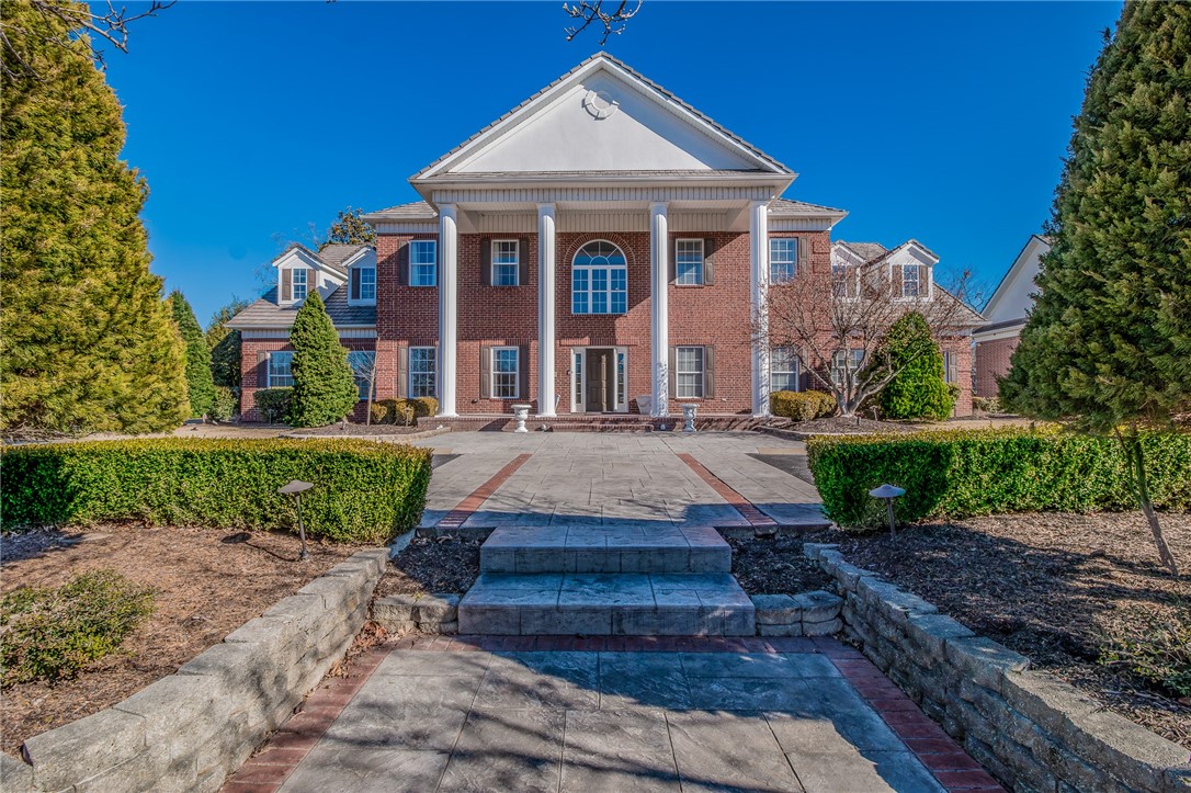 Incredible estate home located in a private gated subdivision on a 1.83-acre cul-de-sac lot, offering rare space and privacy while still minutes from I-49 and Pinnacle Hills amenities. The beautifully landscaped grounds create a park-like backyard setting with abundant space for entertaining, featuring a heated diving pool & spillover spa, large covered outdoor living area with outdoor kitchen, pergola & garden areas. Inside, the chef’s kitchen offers high-end appliances & large island with bar seating open to the living and dining areas—ideal for both entertaining and everyday living. The primary retreat includes a private office & attached exercise room. A guest suite & large family room are also located on the main level, while 3 additional bedrooms upstairs with private bathrooms & oversized walk-in closets. The property also includes a 2,027 SF heated/cooled detached garage with bathroom & storm shelter/safe room, creating an exceptional 6-car garage setup ideal for storage, hobbies, or additional workspace.