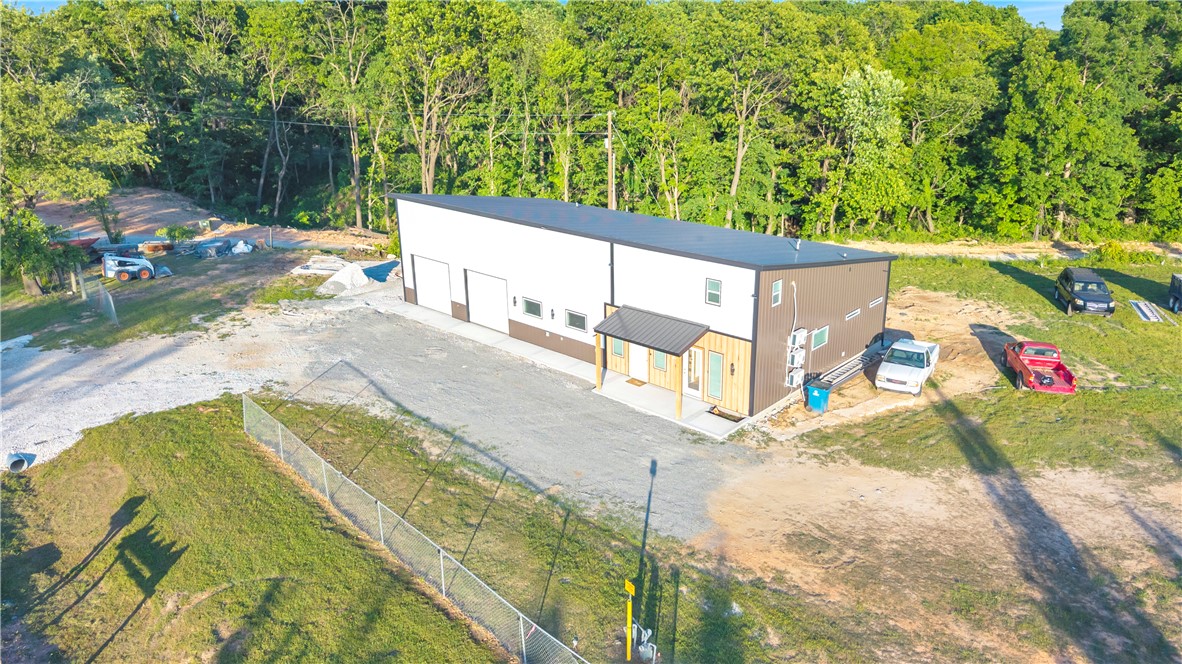 Discover the possibilities with this brand-new commercial shop/flex building offering nearly 3,000 SF of heated and cooled space. Designed for versatility, the property features a private upstairs bedroom with a full bath, ideal for on-site living or staff accommodations. Equipped with two garage doors, including a private bay, this setup is perfect for auto specialists, contractors, e-commerce businesses, and more. Inside features a full kitchen with stainless steel appliances and hood vent, two office spaces, three half baths, and washer/dryer hookups. Ample parking for up to 40 vehicles provides convenience for clients and employees. Located just 8 minutes from XNA Regional Airport in a high-traffic area with excellent visibility, this property offers the perfect combination of functionality, comfort, and exposure for your growing business.