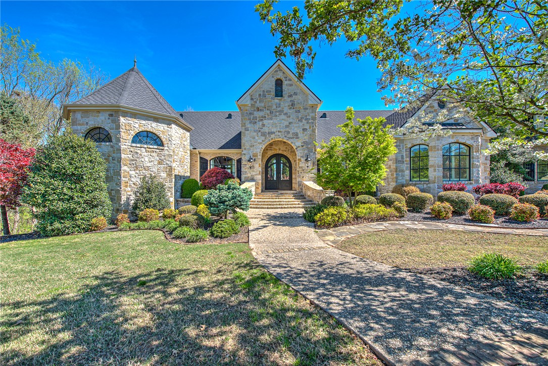 Welcome to an extraordinary French Country estate where luxury, privacy, and breathtaking views come together on 2.3 acres in the gated Beau Chalet community—just minutes from XNA. This award-winning 5,468 sq ft masterpiece, designed by Boyce McQuay and built by Seven Pillars Contracting, makes a lasting impression from the moment you step through its grand iron entry. Inside, you’ll find three stunning living areas, a veranda-access dining room perfect for entertaining, a private executive office with fireplace, and a chef-inspired kitchen. With 4 bedrooms, 4.5 baths, and a private storm shelter, comfort meets peace of mind. Upstairs offers a spacious bonus room, bedroom, full bath, and storage. Step outside to your own private retreat—featuring wraparound covered patios, a resort-style pool with waterfalls, lush landscaping, and a custom fire pit for unforgettable evenings. A Parade of Homes Award winner, this one-of-a-kind residence captures timeless elegance and elevated living in every detail.
