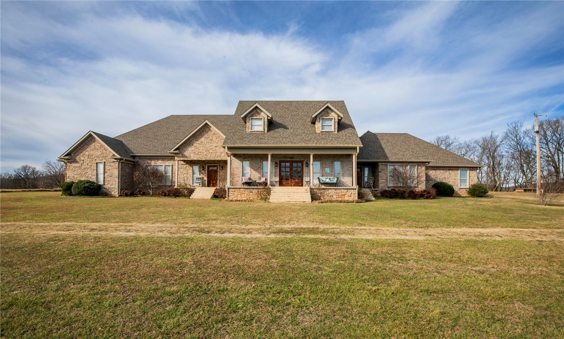 Experience ultimate versatility in this expansive 5,518-square-foot estate, perfectly situated less than one mile from I-49 and under 15 minutes from the heart of Fayetteville. The thoughtfully designed split floor plan features a massive family kitchen that serves as the heart of the home, ideal for both daily living and large-scale entertaining. This home is set up perfectly for multi-family living arrangements with two primary suites, each boasting generous walk-in closets and private finishes.  Also featuring two multi-car garages, both equipped with their own attached workshops for projects or extra storage. The upper level offers a spacious bonus family room along with two additional bedrooms, providing a perfect retreat for guests or children. With a total of seven bedrooms and six and one half bathrooms, there is no shortage of space in this grand residence. This home combines unmatched accessibility to city amenities with the privacy and scale of a true suburban sanctuary.